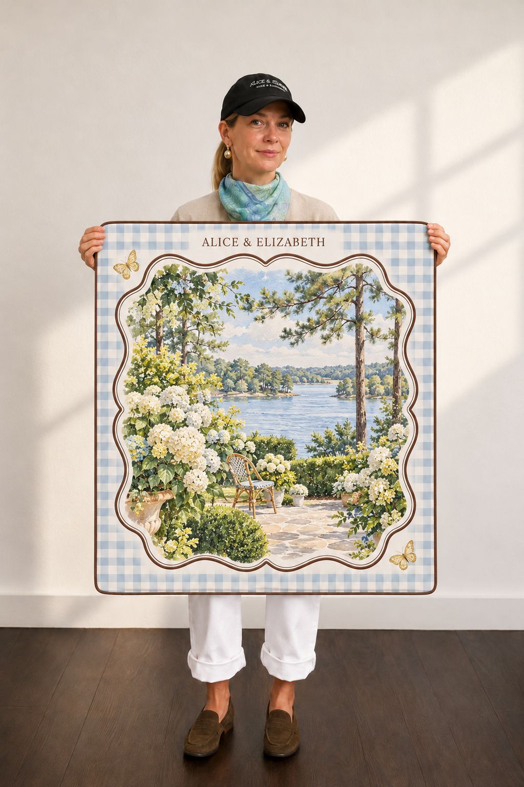Model holding an Alice & Elizabeth custom mat with blue gingham, brown scallops, lake garden artwork and gold butterflies