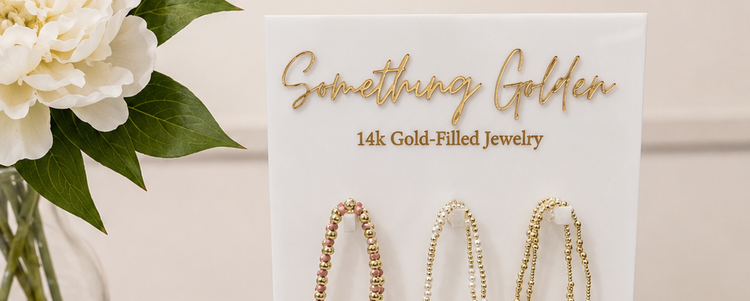 Something Golden 14k gold-filled jewelry display with bracelets and white flowers