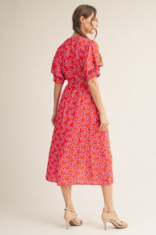 Jodiful Sienna Sunset Abstract Midi Dress featuring vibrant sunset-inspired patterns and flowing fabric on a mannequin.