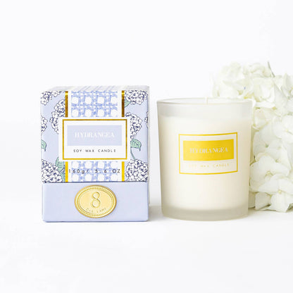 The Lillian Hydrangea Candle by 8 Oak Lane featuring a floral hydrangea design on a white candle in a glass jar.