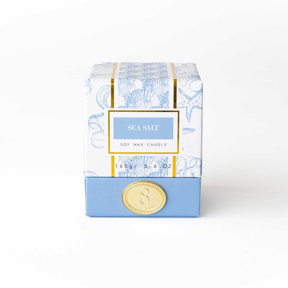 8 Oak Lane sea salt boxed candle with a white ceramic container and a lit wick, emitting a calming glow.