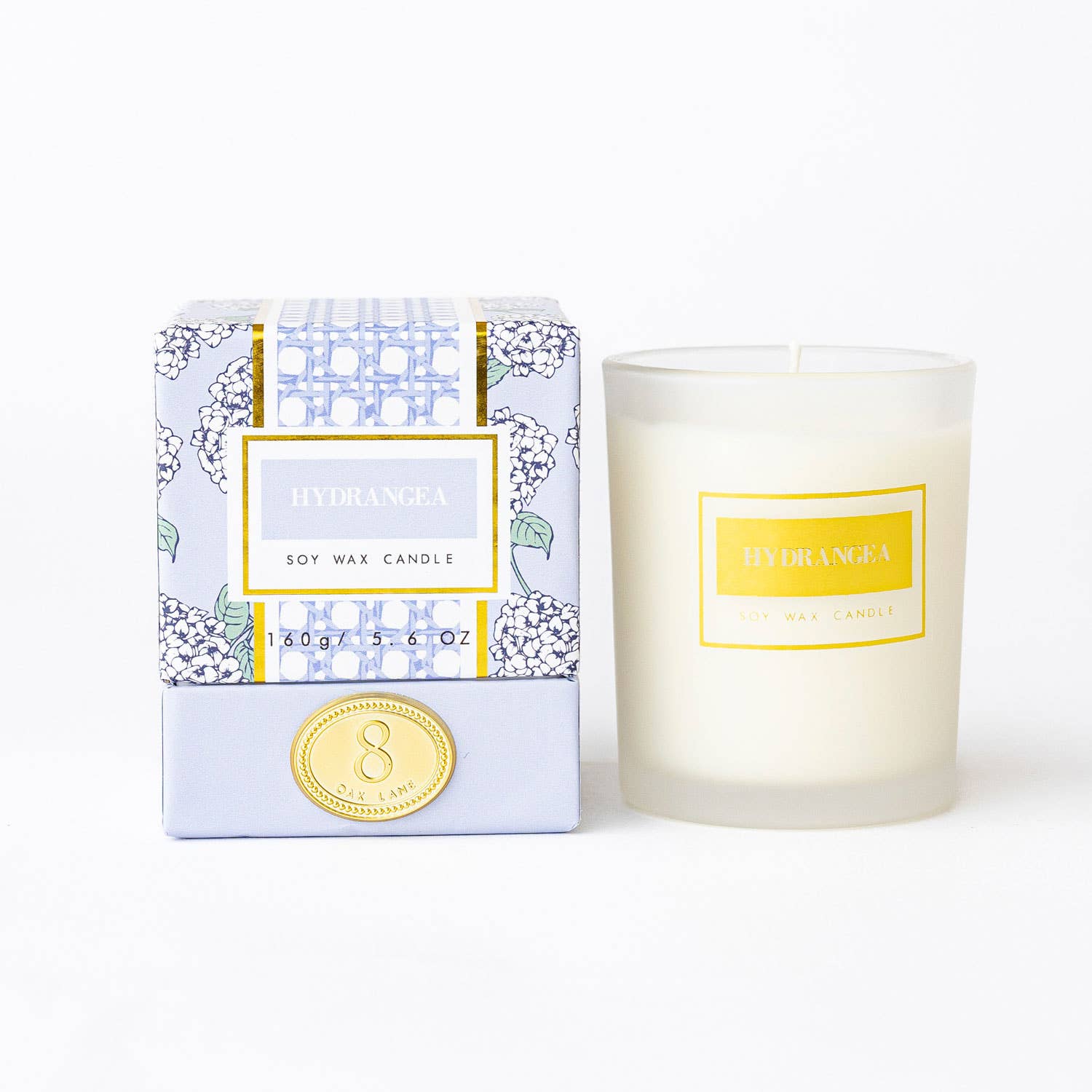 The Lillian Hydrangea Candle by 8 Oak Lane featuring a decorative floral design and a lit wick in a glass jar.