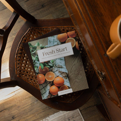 Open devotional book titled "Fresh Start Devotional" by The Daily Grace Co with pages displayed on a table.