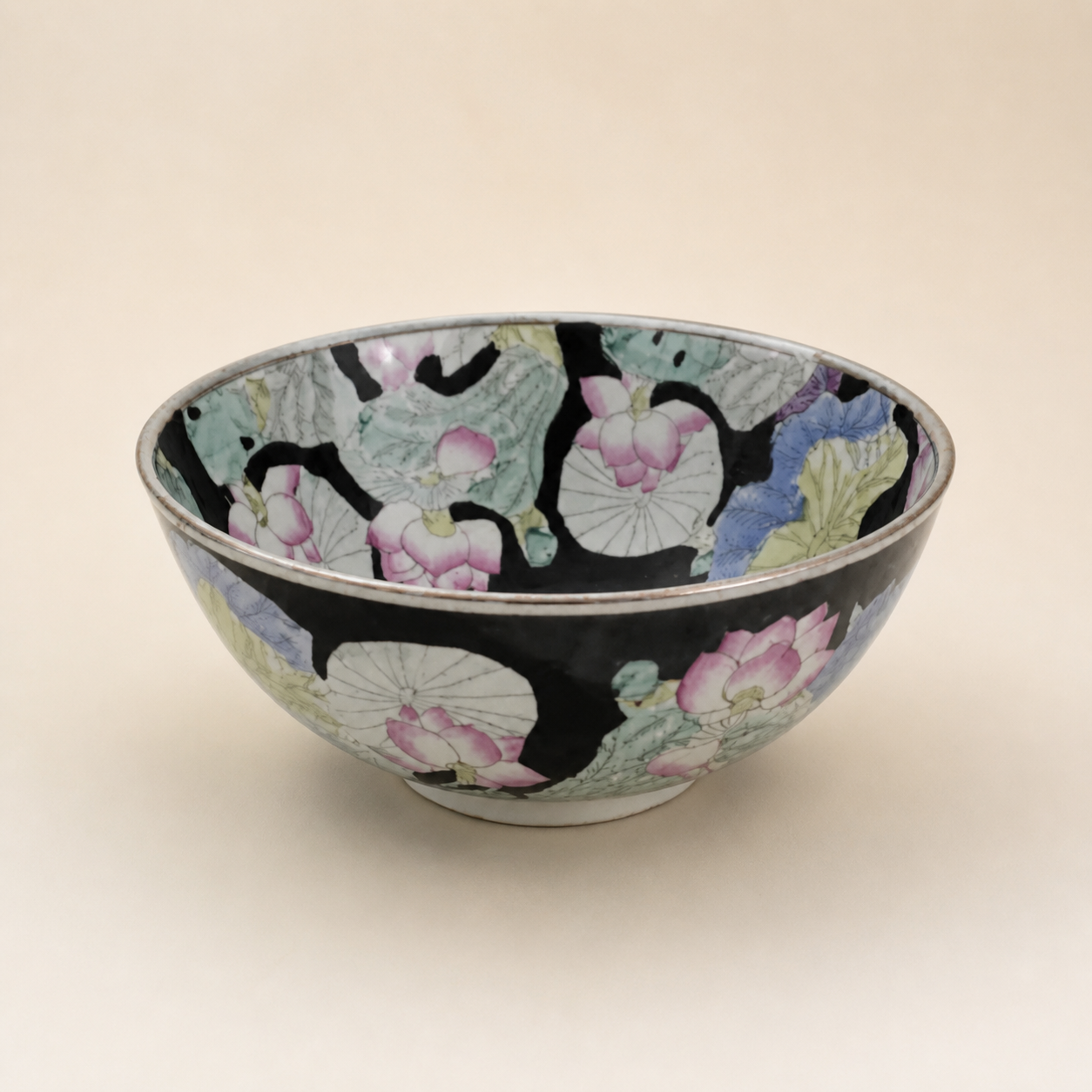 Black-ground famille rose lotus bowl on an ivory studio background