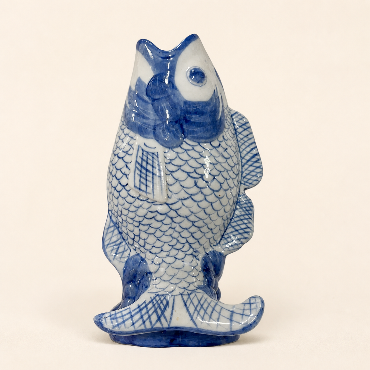 Blue and white porcelain fish-form vase on an ivory studio background