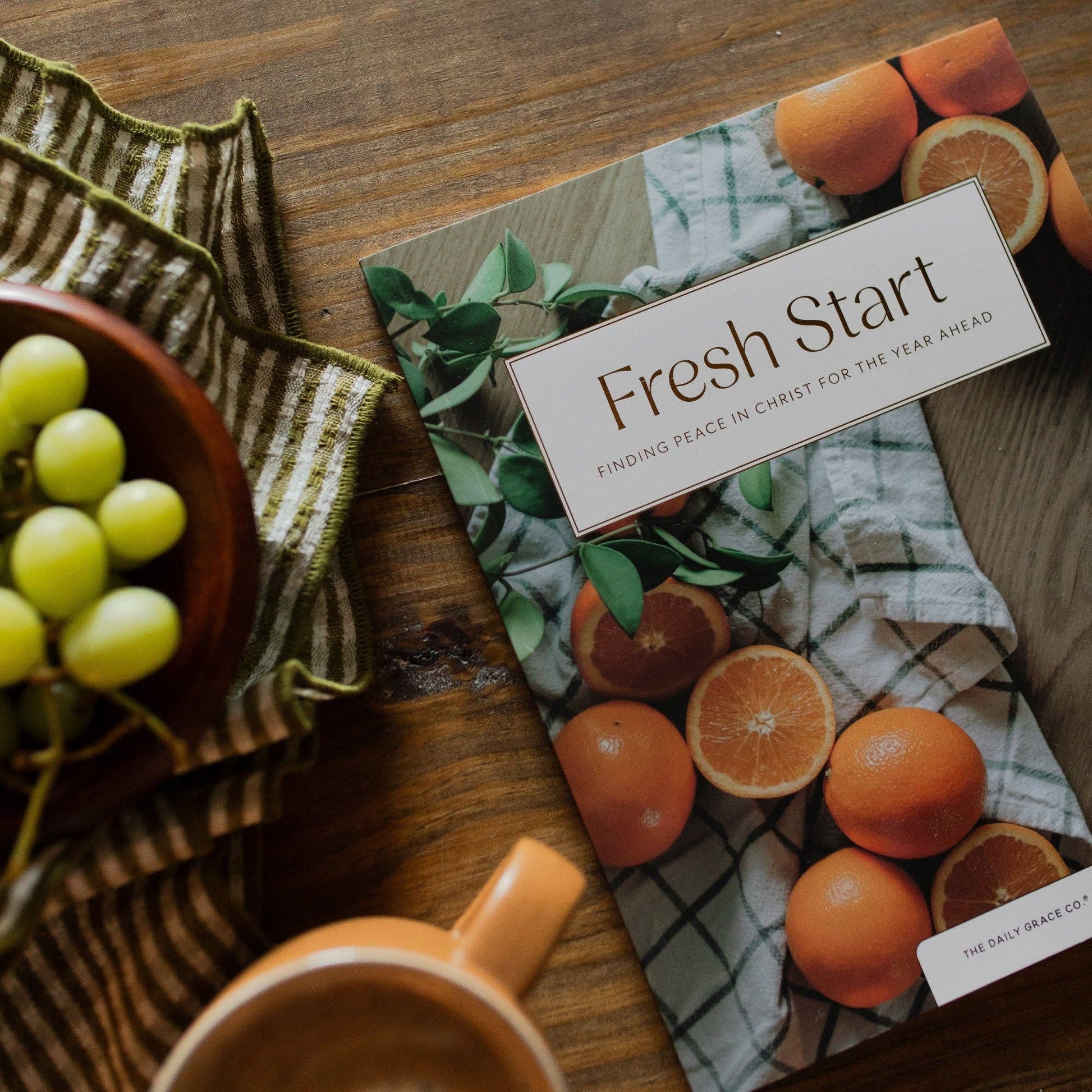Fresh Start Devotional by The Daily Grace Co., open book with highlighted pages and a pen on a cozy wooden table.