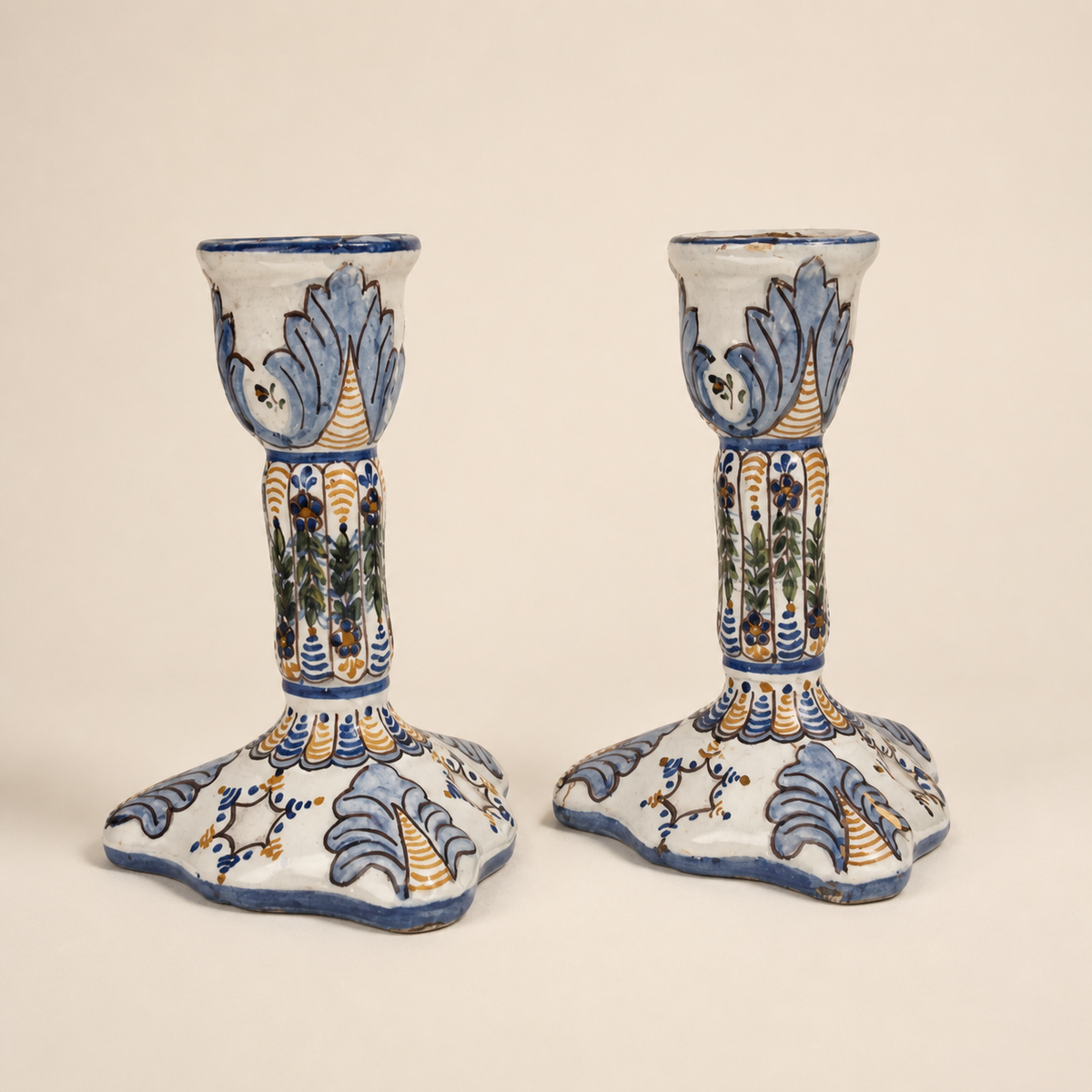 Pair of Portuguese faience candlesticks in as-is repaired condition on an ivory studio background