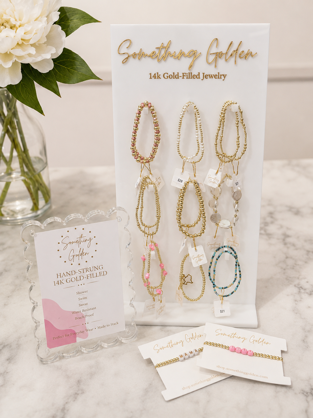 Something Golden 14k gold-filled jewelry displayed with bracelets and white flowers